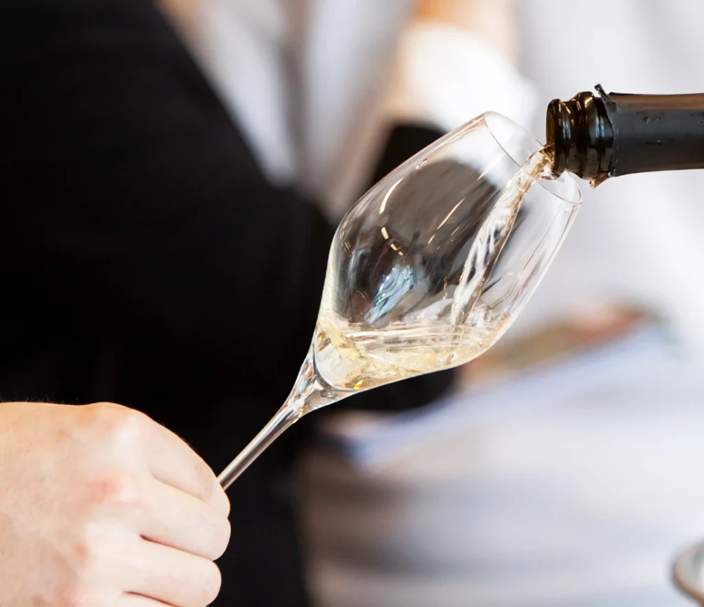 nalievanie šumivého vína z fľaše do pohára počas degustácie vín